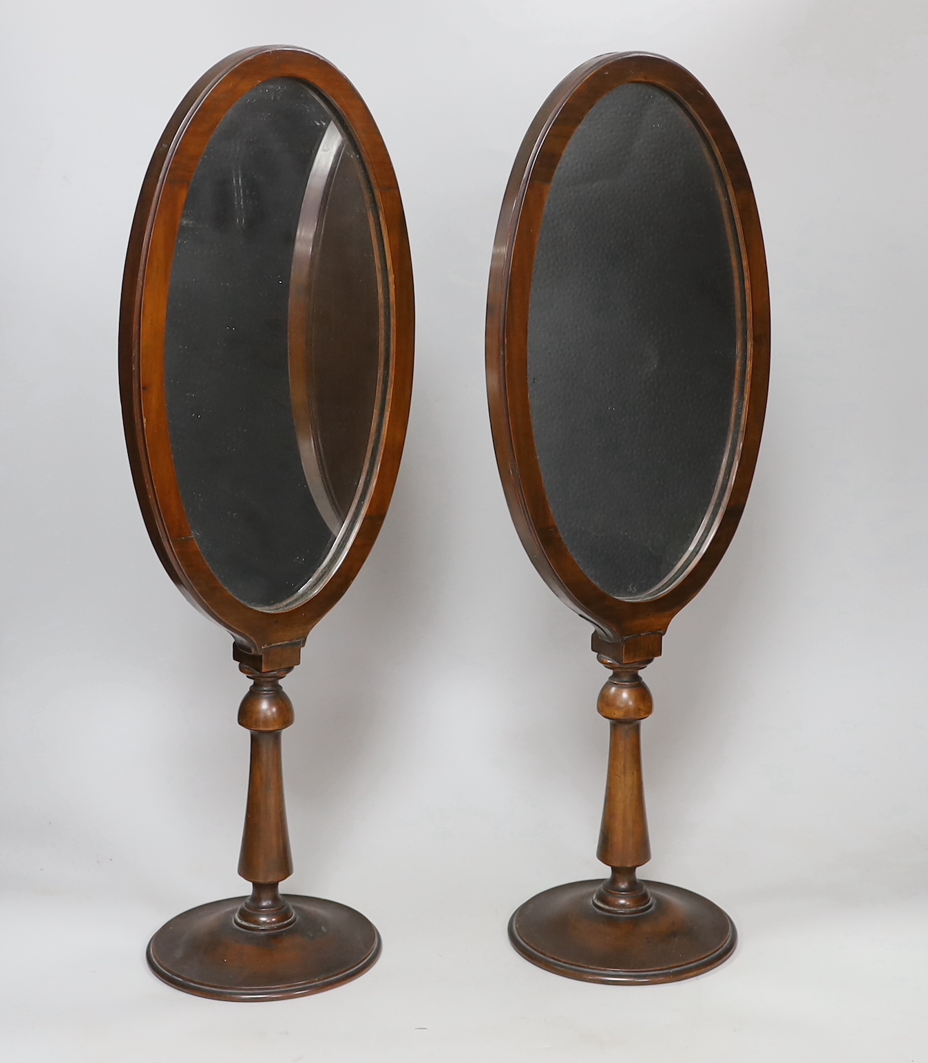 A pair of oval walnut framed shaving mirrors, each 51cm high